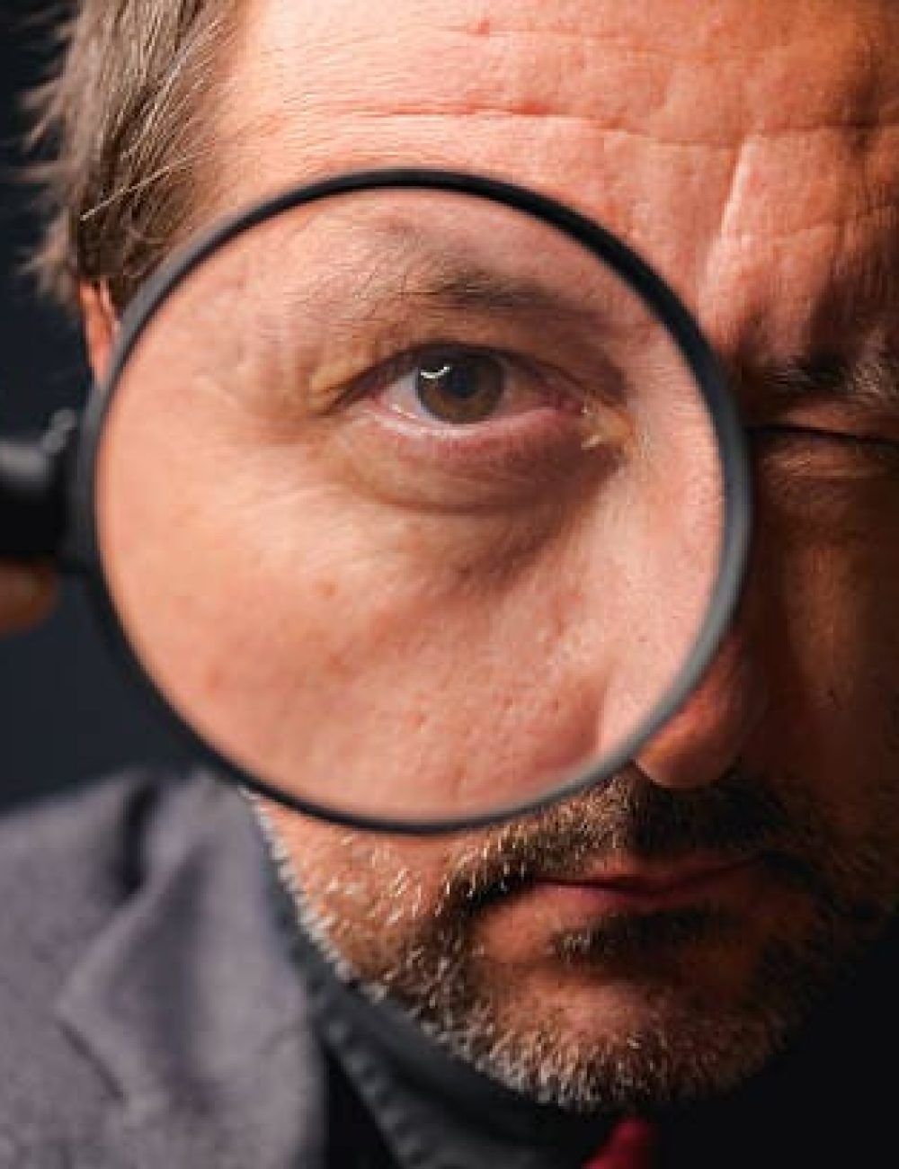 man looking through a magnifying glass hire a private eye